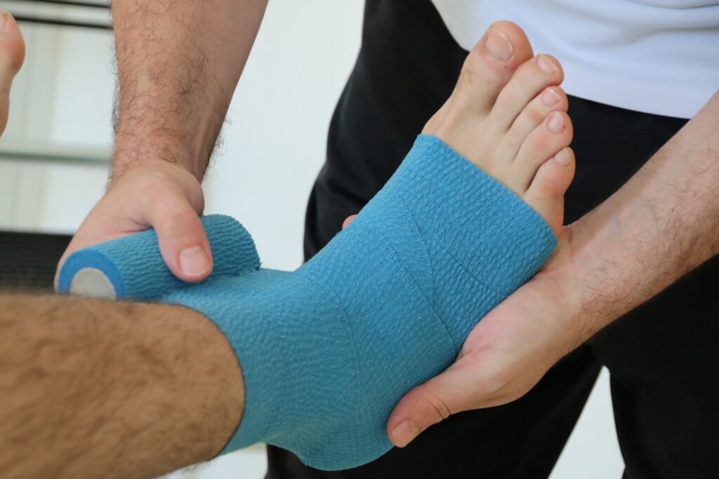Terapista effettua bendaggio attorno alla caviglia di un paziente, presso lo studio fisioterapico Physio Sport Progress.